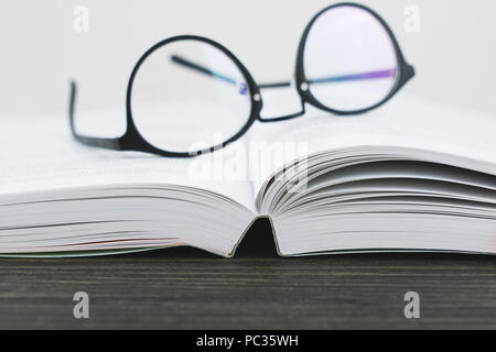 Close up of hipster eyeglasses glasses for reading on an open book, Shallow Depth of Field and selective focus Stock Photo
