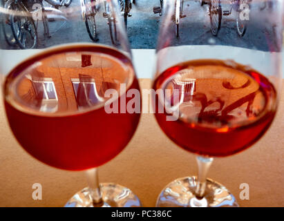 Reflections from windows in rose wine in glasses, bicycles in background Stock Photo