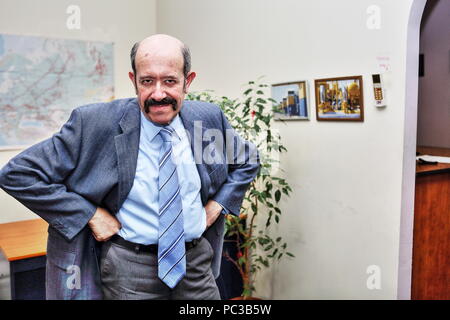 Adult bold man with moustache, the boss in office, is looking angrily with hands a-kimbo, his serious intentions leave next to no hope to his staff Stock Photo