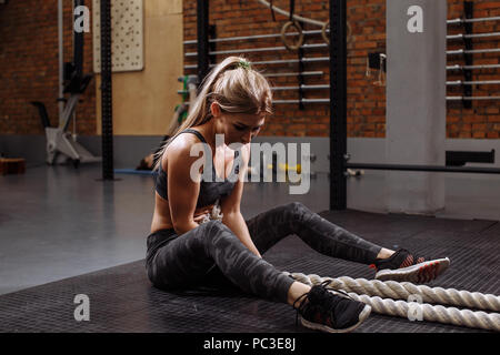 upset thoughtful girl holding the battle ropes in the gym. fulllength side view photo Stock Photo