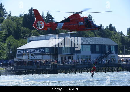 An aircrew aboard an MH-65 Dolphin helicopter from Coast Guard Sector North Bend conducts a rescue swimmer exercise in Coos Bay, Ore., July 19, 2018.    The training was conducted in front of a crowd outside the Coos History Museum & Maritime Collection to showcase some of the operational capabilities of the Coast Guard in the area.    U.S. Coast Guard photo by Petty Officer 3rd Class Trevor Lilburn. Stock Photo