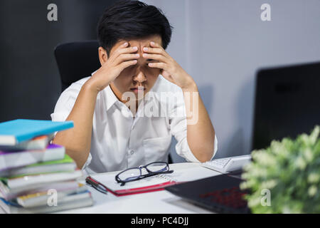 young stressed man studying with book and laptop Stock Photo