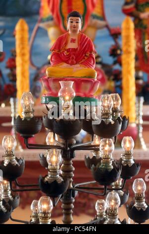 Chua Thiep Long buddhist pagoda. Oil lamps befor Buddha.  Thay Ninh. Vietnam. | usage worldwide Stock Photo
