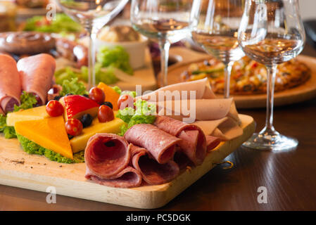 Antipasti platter with different meat and cheese products on wooden board Stock Photo