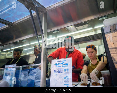 New York, USA. 31st July 2018. Celebrity Chef Marcus Samuelsson, in red, plates food in the Booking.com food truck for their 'Taste of Travel' promotion, in New York on Tuesday, July 31, 2018. Research by Booking.com contends that 51% of American travellers choose their destination based on regional food and drink and the truck served sample dishes from ethnic neighbourhoods in New York such as Richmond Hill and Crown Heights. 'Taste of Travel' is meant to inspire travellers to experience the local cuisine on their trips. (© Richard B. Levine) Credit: Richard Levine/Alamy Live News Stock Photo