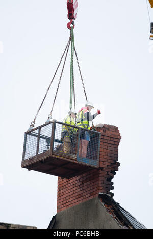 Aberystwyth Wales UK, Wednesday 01 August 2018. After the devastating fire that gutted the Ty Belgrave House hotel on Aberystwyth seafront exactly a week ago, workers in a elevated platform cradle  begin the painstaking task of demoliting  a dangerously damaged   chimney brick by brick.  The structure has to be made safe before the search through the rubble can begin for a missing person, believed to be Lithuanian, who is still unaccounted for. The police have arrested a man on suspicion of arson with intent to endanger life.  Photo © Keith Morris / Alamy Live News Stock Photo
