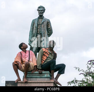 Edinburgh Fringe Festival, Henry Box Brown: Musical Journey photocall, 1st August 2018. Edinburgh, Scotland, UK. The cast at Abraham Lincoln Memorial, Old Calton Burial Ground, which commemorates the  Scots who fought on behalf of the Union in America. Ben Harney and writer Mehr Mansuri create the musical about a 1850s Virginia slave who ships himself to freedom in a box. Black American actors sit at feet of Abraham Lincoln Stock Photo