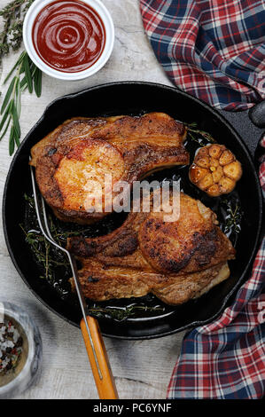 Roasted pork loin steak in a frying pan with tomato sauce Stock Photo