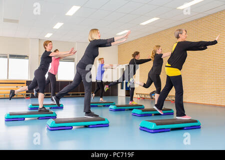 Group of middle aged women with fitness instructor in sportswear leggings  and tops, stretching in the gym before pilates, on a yoga mat near the  large Stock Photo - Alamy