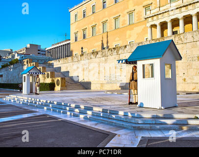 Greek presidential guard, Evzones, standing in front of Monument of the Unknown Soldier and The Greek Parliament. Syntagma Square. Athens Stock Photo