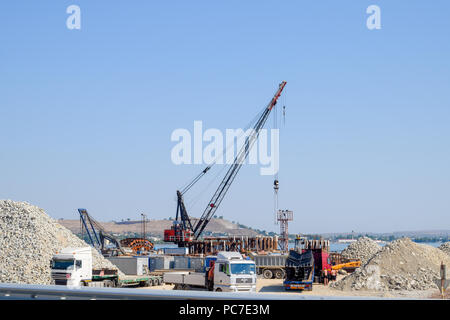 Crimean bridge, Taman, Russia - July 9, 2018: Construction of the Crimean bridge. Piles of rubble and cranes lifted. Construction and repair. Driving  Stock Photo