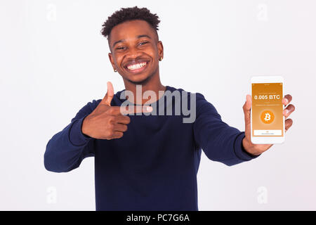 Young African American man pointing his smartphone screen  showing a received crypto currency transaction of bitcoin btc received - Black teenager peo Stock Photo