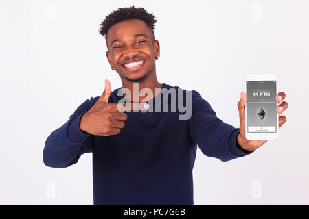 Young African American man pointing his smartphone screen  showing a received crypto currency transaction of ethereum eth received - Black teenager pe Stock Photo