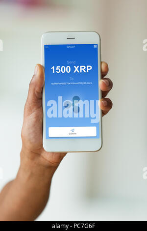 African american person sending a ripple  xrp crypto transaction using  mobile phone wallet - Black people Stock Photo