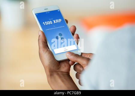 African american person sending a ripple  xrp crypto transaction using  mobile phone wallet - Black people Stock Photo