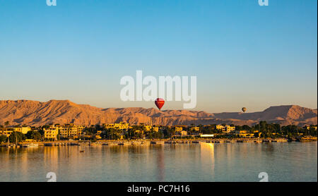View across River Nile towards West Bank and Valley of the Kings with hot air balloons rising in early morning, Luxor, Egypt, Africa
