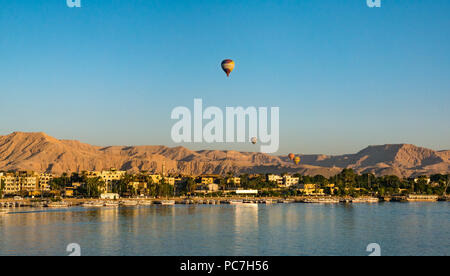 View across River Nile towards West Bank and Valley of the Kings with hot air balloons rising in early morning, Luxor, Egypt, Africa