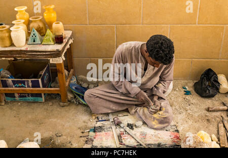 Egyptian workman using carving tool to carve alabaster container in workshop for tourist souvenirs, West Bank, Luxor, Egypt, Africa Stock Photo