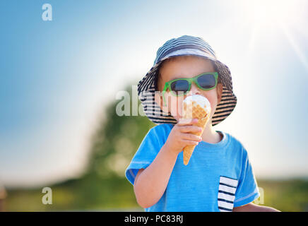 Happy child eating ice cream outdoors in summer Stock Photo