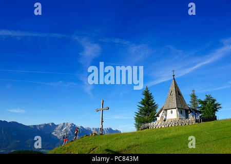 Hiker at the summit of Kraftalm with chapel, in the back Wilder Kaiser, Itter, Kitzbühel Alps, Tyrol, Austria Stock Photo