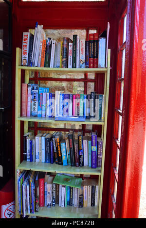 Red telephone kiosk being used as a community book exchange - John Gollop Stock Photo