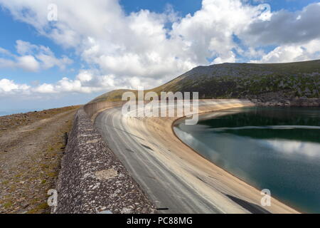 Looking along the dam wall of Llyn Marchlyn Mawr, the upper reservoir of the Dinorwig Hydro Electric pump storage station with the summit of Carnedd Y Stock Photo