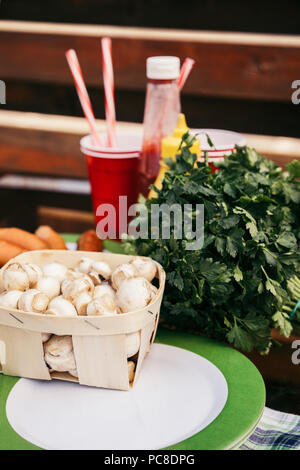 Mushrooms in basket and sausages prepared for grilling outdoors Stock Photo