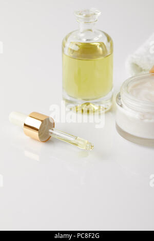 closeup view of organic cream in container, bottle of cosmetic oil, dropper and white towel Stock Photo