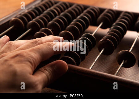 big antique abacus on a wooden table and the hand of man close up Stock Photo