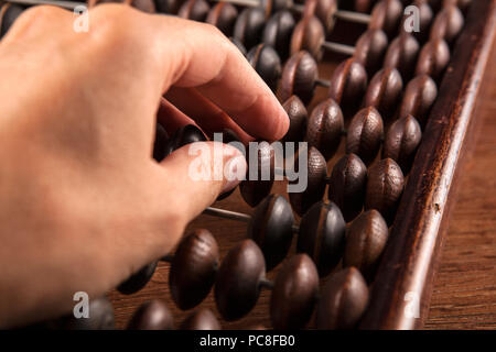 big antique abacus on a wooden table and the hand of man close up Stock Photo