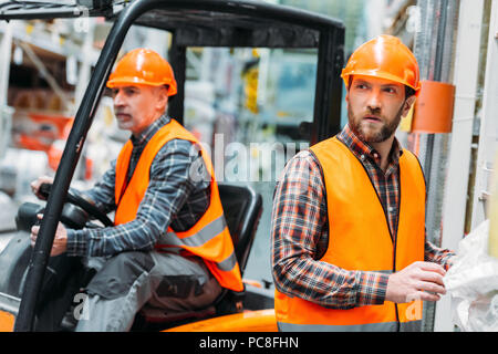 worker and his senior colleague working with forklift machine Stock Photo