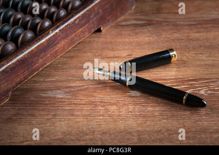 fountain pen on a table with an abacus close up Stock Photo