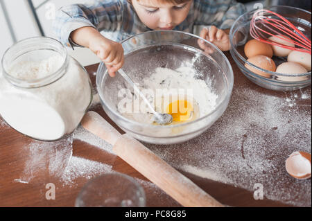 high angle view of little kid preparing dough with flour and egg Stock Photo