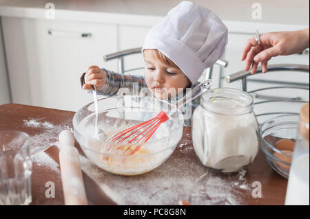 little kid in chef hat preparing dough for cookies Stock Photo