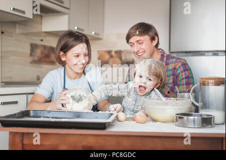 dirty young family cooking with flour together at kitchen Stock Photo