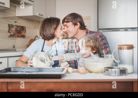 beautiful young family cooking with flour together at kitchen Stock Photo