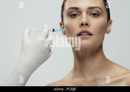 Beautiful woman gets injection in her face. Female under the plastic surgery getting cosmetic injection. Stock Photo