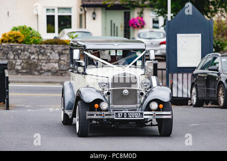 Bride arriving to the church on her wedding day in a vintage Brenchley limousine. Stock Photo