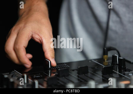 Hand of disc jockey adjusting the crossfader knob while palying live set on party in night club Stock Photo