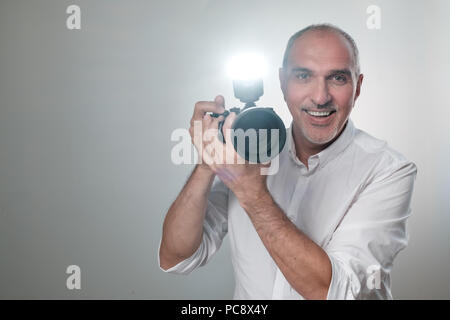 Studio shot of young multi-ethnic Asian man with camera against brown background Stock Photo