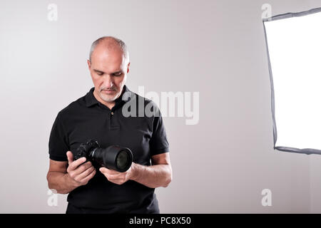 Studio shot of young multi-ethnic Asian man with camera against brown background Stock Photo