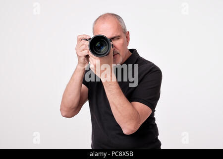 Studio shot of young multi-ethnic Asian man with camera against brown background Stock Photo