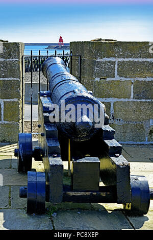 North Shields Cliffords Fort cannon looking over to South Shields Groyne lighthouse Stock Photo