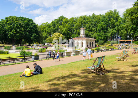 Kensington Gardens, The Italian Gardens with people enjoying the warm summer weather. An ornamental water garden on the north side of Hyde park, near  Stock Photo