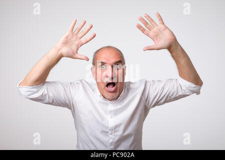 Mature hispanic man is happy with his win. He is holding his fists and shout Wow. Stock Photo