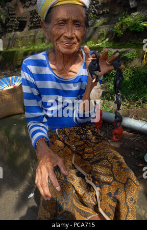 Old lady selling carved monkeys for tourists, Ubud, Bali. Indonesia. Stock Photo