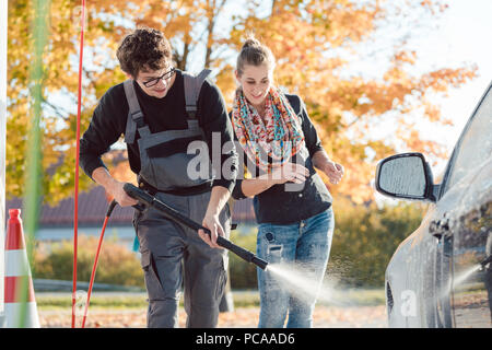 Service man helping woman cleaning her auto in car wash Stock Photo