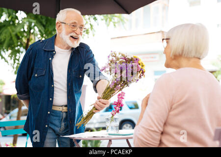 Jolly senior man surprising wife Stock Photo