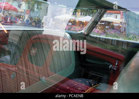 City and houses reflected in the glass of vintage cars on the background of the cabin on the square in the old town of Riga Stock Photo