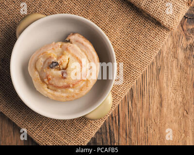 Tasty raisin snail close up on a rustic wooden table, sweet food concept, view from above Stock Photo